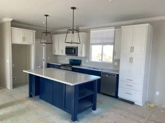 Kitchen remodel with white cabinets and a navy island by TCS Construction